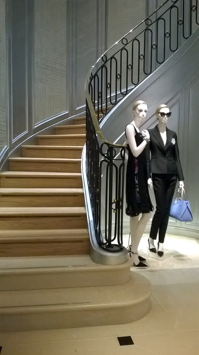 Christian Dior shop mannequins standing next to metal stair balustrade in London shop.